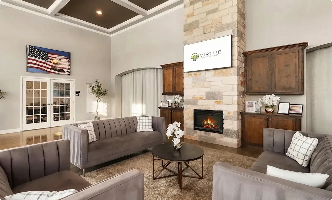 Living room with a stone fireplace and comfortable seating at Ambience Recovery Center in Killeen, Texas